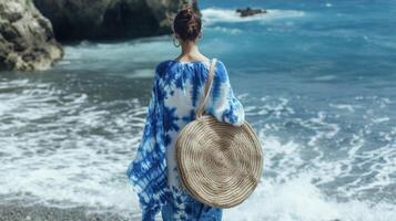 ein lose fließend Kaftan im ein Blau und Weiß gebundenes Auge drucken gepaart mit gewebte huarache Sandalen und ein Rattan Kreis Tasche. diese aussehen ist perfekt zum ein Tag von Insel Erkundung ein foto