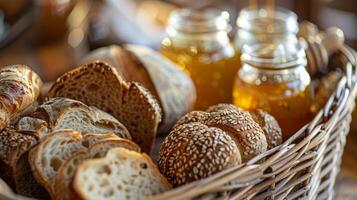 ein Vielfalt von Handwerker Brot von klassisch Weiß zu herzhaft Roggen vereinbart worden im ein Korbweide Korb und serviert mit Gläser von Honig Marmelade und Butter foto