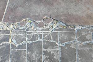 Zement Oberfläche von das Straße oder Gehweg ist geknackt im lange Linien. foto