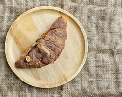 Schokolade Croissants dekoriert mit Kakao Pulver und Mandeln auf ein hölzern Platte. oben Aussicht foto