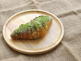 Grün Tee Matcha Croissants ausgestopft mit rot Bohne Einfügen auf hölzern Platte. Seite Aussicht foto