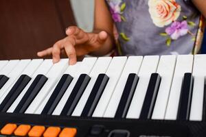 asiatisch süß Mädchen spielen das Synthesizer oder Klavier. süß wenig Kind Lernen Wie zu abspielen Klavier. Kinder Hände auf das Tastatur drinnen. foto