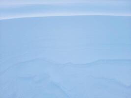 Schnee Textur. das Wind im das Tundra und im das Berge formt Muster und Grate auf das Schnee Oberfläche. Winter Hintergrund foto