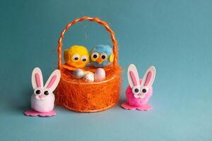 Spielzeug Eier mit Vögel im ein Orange Korb und Ostern Hasen auf ein Blau Hintergrund. foto