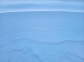 Schnee Textur. das Wind im das Tundra und im das Berge formt Muster und Grate auf das Schnee Oberfläche. Winter Hintergrund foto