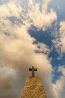 Silhouette von Stein Grab Kreuz gegen das Hintergrund von ein Blau Abend Himmel mit Wolken foto