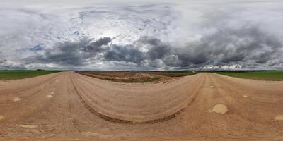 hdri 360 Panorama auf nass Kies Straße unter Felder im Frühling böse Tag mit Sturm Wolken im gleichwinklig voll nahtlos kugelförmig Projektion, zum vr ar virtuell Wirklichkeit Inhalt foto