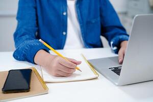 asiatisch Teenager Schüler schreiben Hausaufgaben mit Laptop Computer, Lernen Universität Bildung Konzept. foto