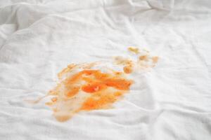 schmutziger tomatensaucenfleck oder ketchup auf tuch zum waschen mit waschpulver, reinigungskonzept für die hausarbeit. foto