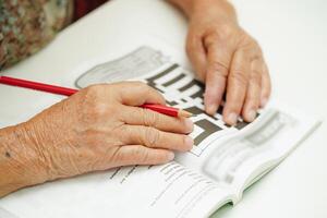 Alten Frau spielen Sudoku Puzzle Spiel zum Behandlung Demenz Verhütung und Alzheimer Krankheit. foto