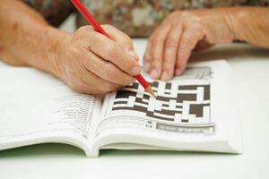 Alten Frau spielen Sudoku Puzzle Spiel zum Behandlung Demenz Verhütung und Alzheimer Krankheit. foto