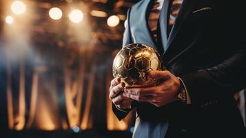 ein Mann ist halten ein Gold Fußball Ball im seine Hand foto