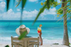 ein Mann ist Sitzung auf ein Strand Stuhl mit ein trinken im seine Hand foto