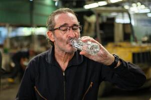 Fabrik Arbeitskräfte Arbeit und trinken Wasser während Arbeiten foto