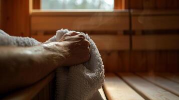 ein Nahansicht von ein Patienten Hand halten auf zu ein Handtuch wie Sie genießen das beruhigend Hitze von das Sauna mit diese Zeit zu Freisetzung Spannung und Stress von ihr Körper. foto