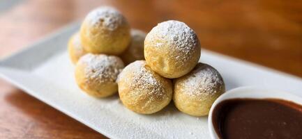 hausgemacht Niederländisch poffertjes Mini Pfannkuchen mit Glasur pulverisiert Zucker und Schokolade Füllungen mit zusätzlich Schokolade Soße foto