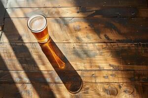 Overhead Aussicht von ein einsam Bier Glas auf ein einfach hölzern Tisch, Betonung auf bilden und Licht foto