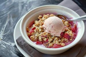 Scoop von Erdbeere Eis Sahne mit Rhabarber Kompott und bröckelte Hafer Belag im ein Weiß Schüssel, Ideal zum Sommer- Menüs und Dessert Rezepte foto