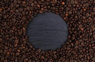 rahmen aus gerösteten kaffeebohnen auf schwarzem tisch, draufsicht foto