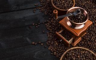 Boden Kaffee, Kaffee Mühle, Schüssel von geröstet Kaffee Bohnen auf schwarz hölzern Hintergrund, oben Aussicht foto