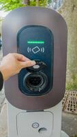 schließen oben von ein Hand interagieren mit ein elektrisch Fahrzeug Laden Bahnhof, symbolisieren nachhaltig Transport und Umwelt Bewusstsein foto