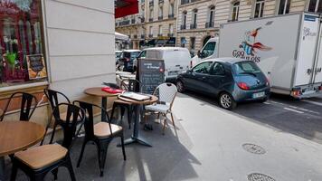 leeren draussen Cafe Sitzplätze im Paris, Frankreich, mit geschäftig Straße Leben und Vorbeigehen Fahrzeuge, gefangen auf April 14., 2024, illustrieren städtisch europäisch Kultur foto