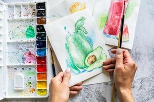 Draufsicht auf handgezeichnete Aquarellillustration und Werkzeuge zum Zeichnen foto