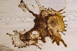 Kaffee Flecken auf Weiß hölzern Tisch. Holz Textur Hintergrund. groß dunkel braun dramatisch Spritzer, Fleck, Spritzen, Stelle, Tropfen von schwarz Kaffee. Muster, Hintergrund. oben Sicht. Nahaufnahme. Kopieren Raum. foto