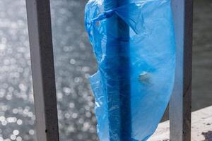 Blau Plastik Tasche hängend auf das Geländer von elisabeth Brücke Über Donau Fluss im Budapest. Müll im das Stadt. Umwelt Verschmutzung Konzept. ökologisch Katastrophe, Katastrophe. selektiv Fokus foto