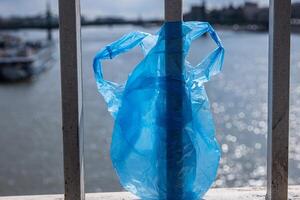 Blau Plastik Tasche hängend auf das Geländer von elisabeth Brücke Über Donau Fluss im Budapest. Müll im das Stadt. Umwelt Verschmutzung Konzept. ökologisch Katastrophe, Katastrophe. selektiv Fokus foto