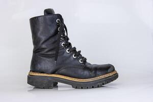 alt benutzt gebrochen schwarz Leder Heer Spitze Stiefel. modisch Herbst Stiefel. stilvoll Damen Herren unisex Grunge Stiefel mit Schnürsenkel. hoch Militär- Schuhe isoliert auf Weiß Hintergrund. eben legen. Kopieren Raum foto