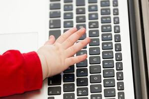 Hand von ein Neugeborene Baby mit ein Laptop Tastatur foto