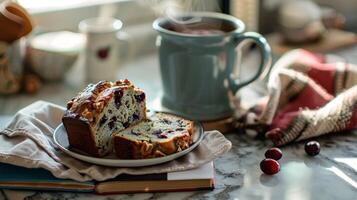 ein gemütlich Küche Szene mit ein dämpfen Tasse von Tee ein Scheibe von Cranberry Nussbaum Brot und ein Buch ruhen auf ein Marmor Arbeitsplatte foto