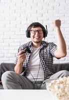 aufgeregter junger Mann, der zu Hause Videospiele spielt und seinen Sieg genießt foto