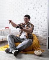 lustiger junger Mann, der zu Hause Videospiele spielt foto