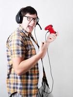 aufgeregter junger Mann, der Videospiele spielt und einen Joystick auf grauem Hintergrund hält foto