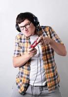 lustiger junger Mann, der Videospiele spielt und einen Joystick auf grauem Hintergrund hält foto