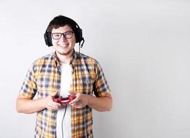 lächelnder junger Mann, der Videospiele mit einem Joystick auf grauem Hintergrund spielt