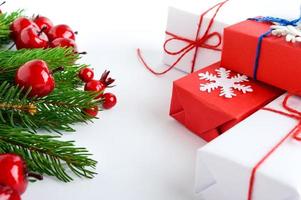 Weihnachten, Neujahr Thema. feierlicher Hintergrund. Geschenkboxen, grüne Fichtenzweige, dekorative rote Beeren auf Weiß. Grußkarte. Frohe Weihnachten.