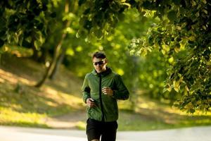 athletischer junger Mann, der beim Training im sonnigen grünen Park läuft foto