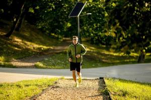 athletischer junger Mann, der beim Training im sonnigen grünen Park läuft