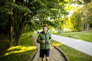 athletischer junger Mann, der beim Training im sonnigen grünen Park läuft foto