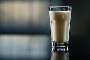 elegant Glas von Milch auf ein reflektierend Oberfläche mit ein schwarz zu grau Gradient Hintergrund, anspruchsvoll aussehen foto