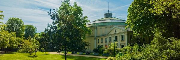 elegant neoklassisch Gebäude umgeben durch üppig Grün im ein heiter Park Einstellung, Ideal zum Freizeit, Kultur thematisch Inhalt, und Frühling Ferien foto