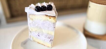 Scheibe von Blaubeere Kuchen dekoriert mit frisch Beeren auf Weiß Platte, köstlich geschichtet Kuchen, oben Aussicht foto