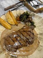 Lendenstück Steak gegrillt Mittel Selten serviert mit Kartoffeln und Salat mit Pilz schwarz Pfeffer Soße im ein Restaurant foto