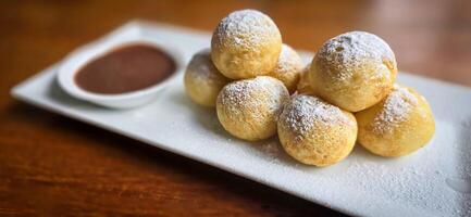 hausgemacht Niederländisch poffertjes Mini Pfannkuchen mit Glasur pulverisiert Zucker und Schokolade Füllungen mit zusätzlich Schokolade Soße foto