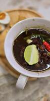 Rohon oder indonesisch schwarz Rindfleisch Suppe, schwarz Farbe sind von indonesisch Nuss namens Kluewek. serviert mit Kalk, Chili Paste, gesalzen Ei, und tempe Cracker. perfekt zum Rezept, Artikel, oder irgendein Kochen foto