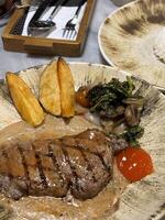Lendenstück Steak gegrillt Mittel Selten serviert mit Kartoffeln und Salat mit Pilz schwarz Pfeffer Soße im ein Restaurant foto