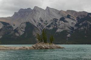 wolkig Tag auf felsig Insel im See Minnewanka, kanadisch felsig Berge, banff National Park foto